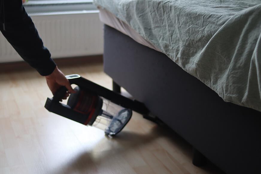 Man sieht den Shark Anti Hair Wrap Flexoloxy bei der Reinigung unter Möbeln.